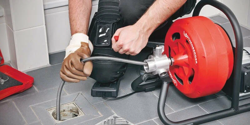 Plumber using a drain-cleaning machine in Palm Springs