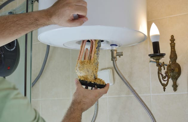 Technician removing mineral buildup from a water heater in Palm Springs